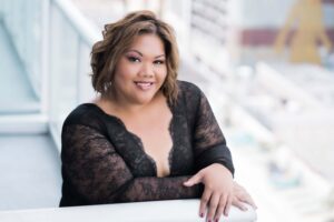 Plus size woman wearing black long sleeve lace top posing on a balcony for a boudoir photoshoot