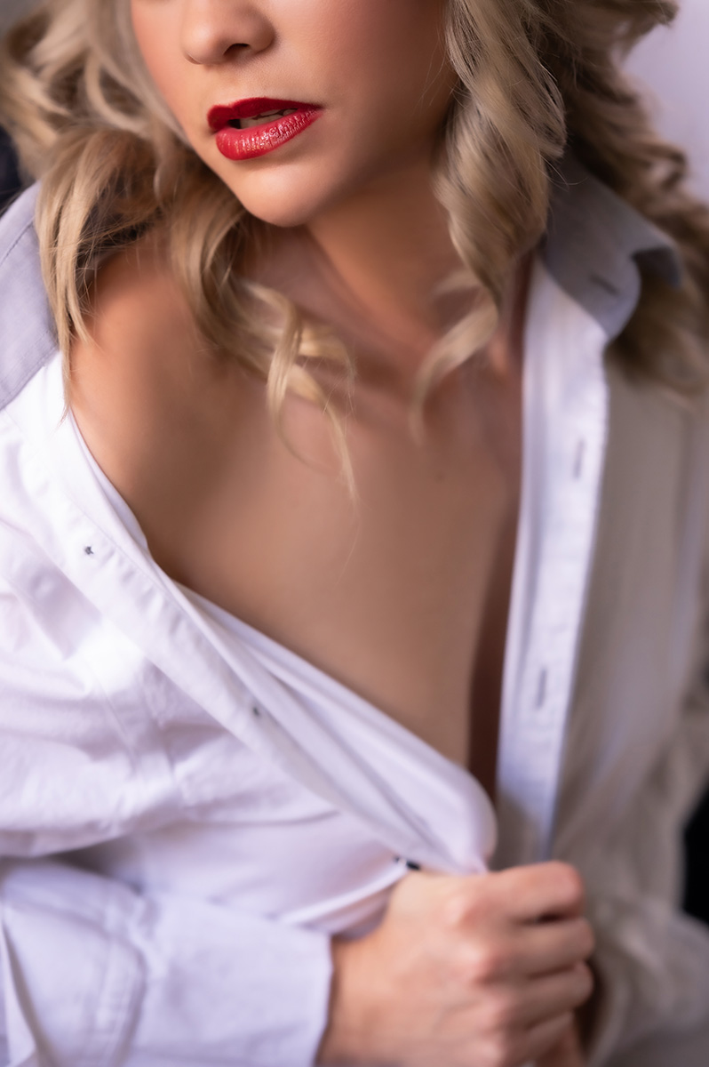 Close up boudoir portrait of blonde woman wearing red lipstick posed with a white long sleeve shirt draped over her shoulders