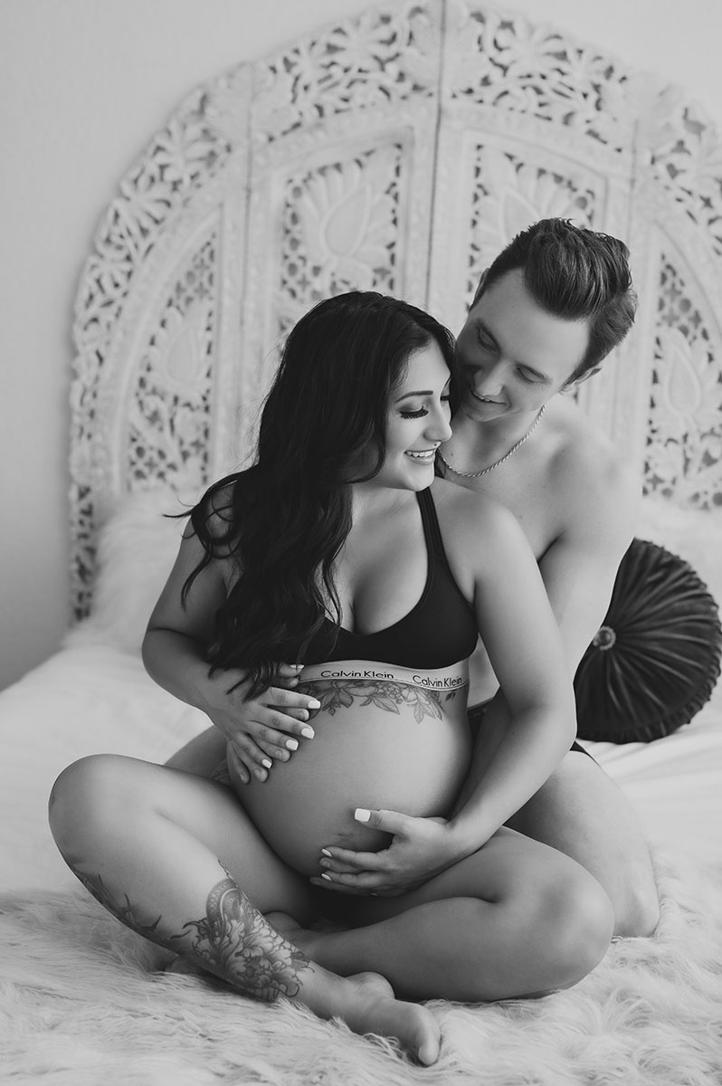 Black and white couples portrait of a pregnant woman and a man embracing her